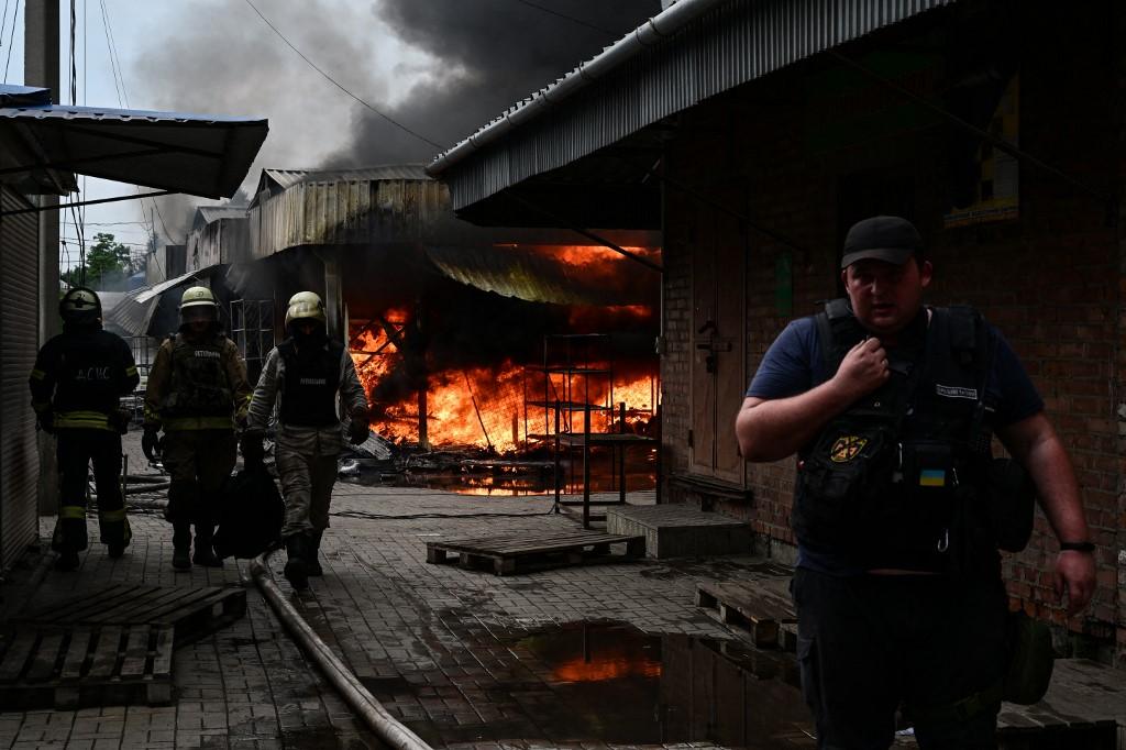 Des pompiers s'affairent à contrôler les flammes dans un marché de Sloviansk touché par un missile russe début juillet. [AFP - Miguel Medina]