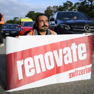 Un activiste de Renovate Switzerland sur l'A1 près de Lausanne, le 4 octobre 2022. [Keystone - Laurent Gillieron]