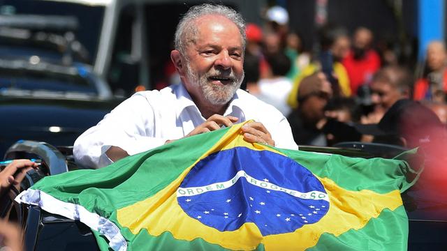 Lula porte un drapeau brésilien à sa sortie du bureau de vote à Sao Paulo, le 30 octobre 2022. [AFP - Carl De Souza]