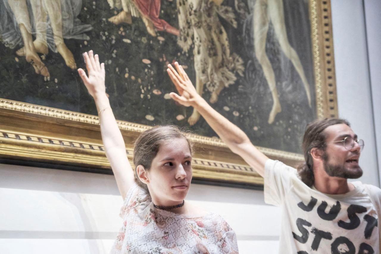 Deux militants ont déployé une banderole au pied du "Printemps" de Botticelli et collé leur main à la vitre qui protège le chef-d'œuvre au musée des Offices à Florence, le 22 juillet 2022. [REUTERS - ULTIMA GENERAZIONE]
