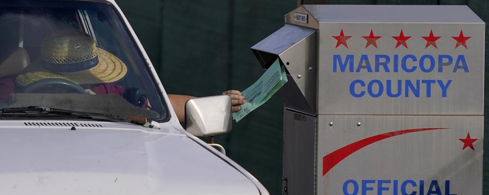 Un électeur dépose son vote dans une urne de rue à Phoenix en Arizona. [Keystone/AP Photo - Matt York]