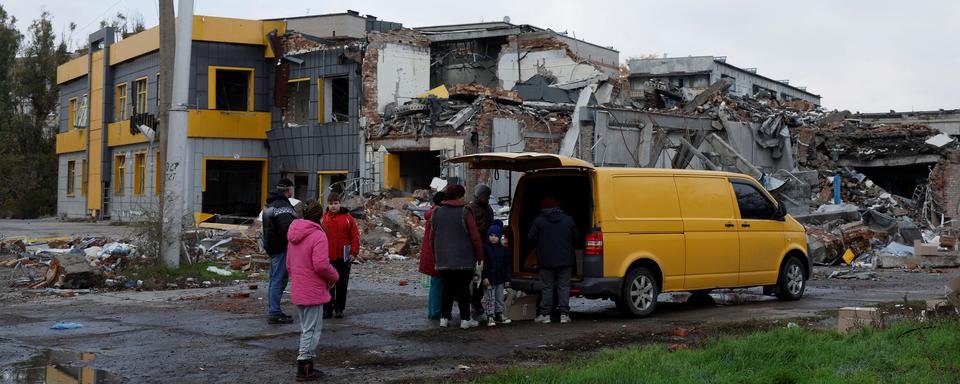 Des civils de Bakhmout sortent de leurs abris pour collecter une aide alimentaire, devant un bâtiment complètement détruit, le 30 octobre 2022. [reuters - Clodagh Kilcoyne]