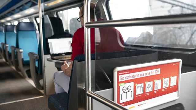 Un homme assis dans un train entre Zurich et Berne le 6 janvier 2021. [Keystone - Gaetan Bally]