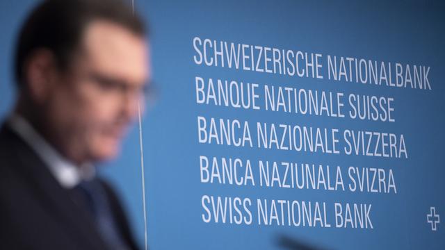 Le président de la Banque nationale suisse Thomas Jordan s'efface devant le logo de l'institut lors d'une conférence de presse en 2018. [Keystone - Anthony Anex]