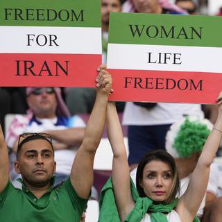 Lundi 21 novembre: un homme et une femme brandissent des pancartes pour la liberté en Iran lors du match du Mondial entre l'Iran et l'Angleterre au Qatar. [Keystone - AP Photo/Alessandra Tarantino]