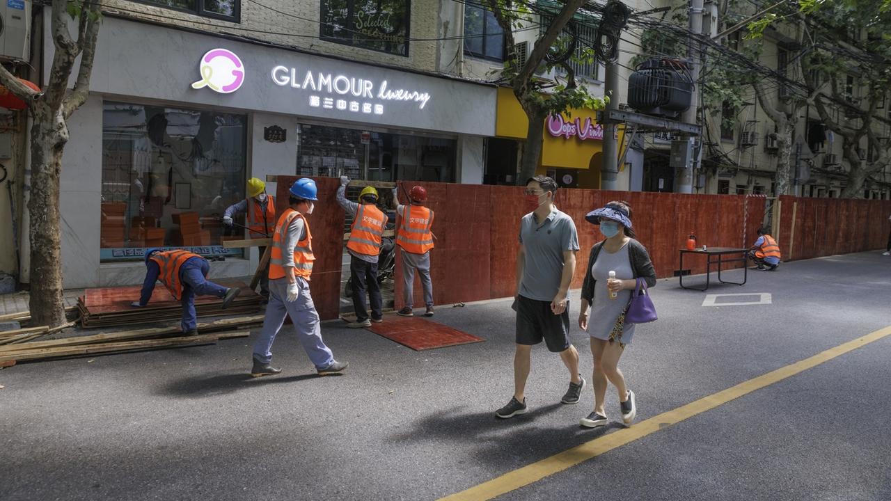 Des personnes passent devant des travailleurs qui démontent des barrières avant la levée du confinement à Shanghai, en Chine, le 31 mai 2022. [Keystone - EPA/ALEX PLAVEVSKI]