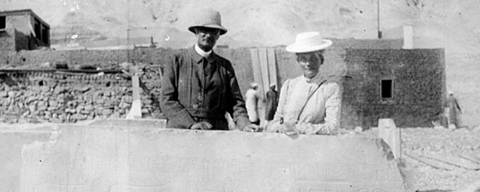 Photographie (négatif) faite lors des fouilles du temple du roi Montouhotep Nebhépetrê à Deir el-Bahari en 1905. Edouard Naville et une femme (Marguerite Naville ?) posent derrière une des grandes parois du sarcophage de Kaouit, découvert à Deir el-Bahari. [Musée d'art et d'histoire, Genève - Orme]