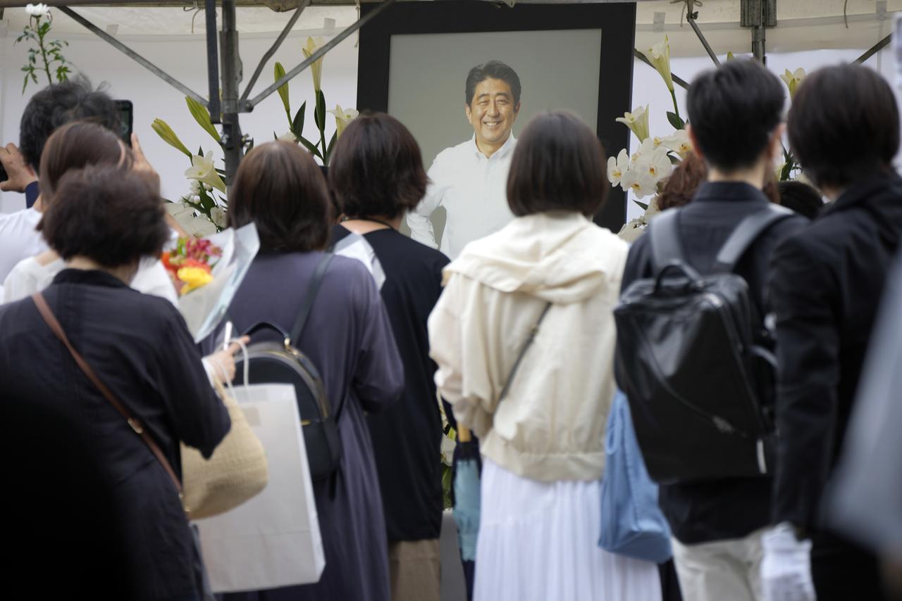 Des personnes font la queue pour offrir des fleurs et prier pour l'ancien Premier ministre Shinzo Abe, au temple Zojoji, avant ses funérailles, mardi 12 juillet 2022, à Tokyo. [KEYSTONE - Eugene Hoshiko / AP Photo]