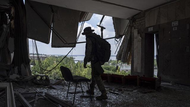 Un soldat ukrainien se promène dans le bâtiment détruit de l'administration militaire régionale de la ville de Mykolaïv. [Keystone/AP Photo - Evgeniy Maloletka]