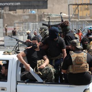 Des membres des milices partisanes de Moqtada Sadr quittent la Zone Verte de Bagdad. [Keystone/EPA - Murtaja Lateef]
