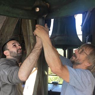 Elie Darbellay (à gauche) et Beat Jaggy (à droite) en pleine action pour réparer le carillon de la plus ancienne – et la plus haute – église de Martigny. [RTS - Christophe Canut]
