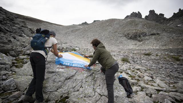 Le drapeau de l'initiative pour les glaciers déposé sur le Pizol, un glacier en voie de disparition. [Keystone - Gian Ehrenzeller]