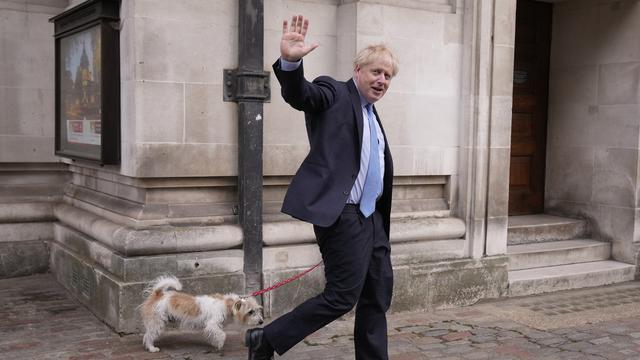 Le Premier ministre britannique Boris Johnson salue les médias alors qu'il part avec son chien Dilyn après avoir voté dans un bureau de vote à Londres, pour les élections municipales, jeudi 5 mai 2022. [AP Photo/KEYSTONE - Matt Dunham]