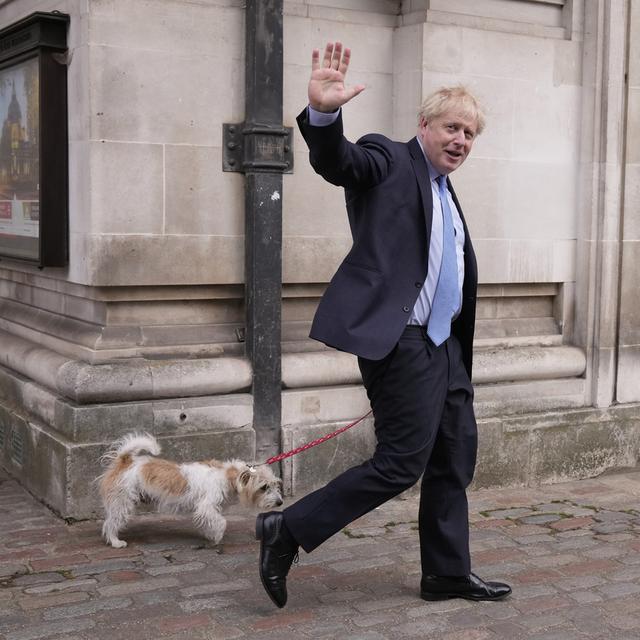 Le Premier ministre britannique Boris Johnson salue les médias alors qu'il part avec son chien Dilyn après avoir voté dans un bureau de vote à Londres, pour les élections municipales, jeudi 5 mai 2022. [AP Photo/KEYSTONE - Matt Dunham]