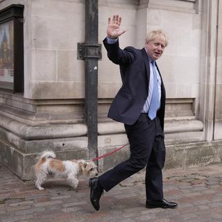 Le Premier ministre britannique Boris Johnson salue les médias alors qu'il part avec son chien Dilyn après avoir voté dans un bureau de vote à Londres, pour les élections municipales, jeudi 5 mai 2022. [AP Photo/KEYSTONE - Matt Dunham]