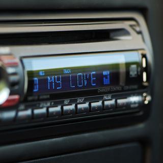 Gros plan sur un poste de radio de voiture affichant "my love". [Depositphotos - _luSh_]