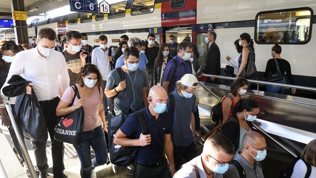 Des voyageurs portant le masque dans la gare de Lausanne. [Keystone - Laurent Gillieron]