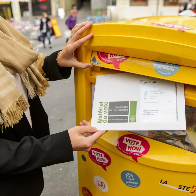 Une personne envoie son bulletin de vote par la Poste. [Keystone - Jean-Christophe Bott]