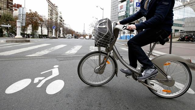 Une personne utilise un vélo en libre-service Velib entre deux voitures à Paris, le mardi 30 octobre 2012. [AP Photo/KEYSTONE - Francois Mori]