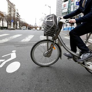 Une personne utilise un vélo en libre-service Velib entre deux voitures à Paris, le mardi 30 octobre 2012. [AP Photo/KEYSTONE - Francois Mori]