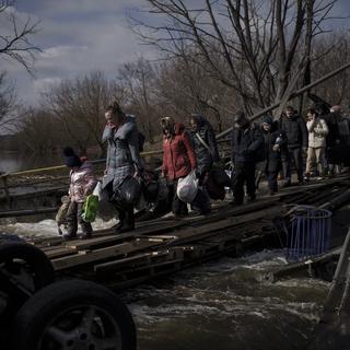 Ukrainiens traversant un pont détruit près de Kiev le 9 mars 2022. [AP Photo - Felipe Dana - Keystone]