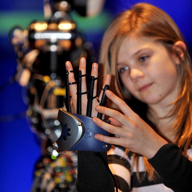 Une fille teste un gant de réalité virtuelle. [Keystone - EPA/Andy Rain]