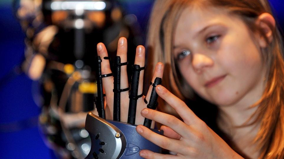 Une fille teste un gant de réalité virtuelle. [Keystone - EPA/Andy Rain]