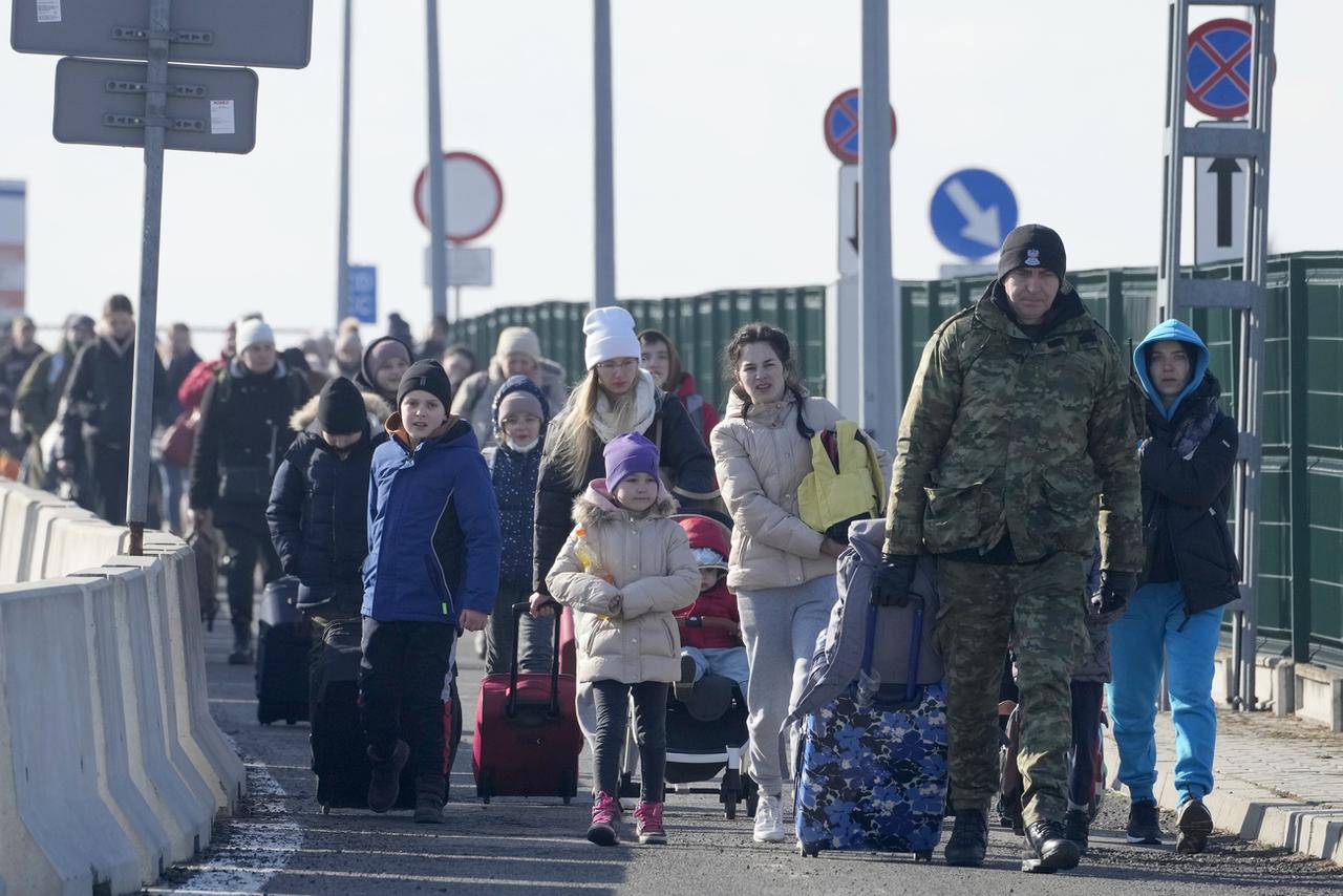 Un garde-frontière aidant des réfugiés ukrainiens arrivant à la frontière polonaise. [AP Photo/Keystone - Czarek Sokolowski]