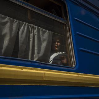 Une jeune fille déplacée regarde à travers la fenêtre d'un train en direct de l'Est de l'Ukraine. Le problème des enfants déplacés est particulièrement aigu, en particuliers lorsqu'il s'agit d'enfants ukrainiens déplacés de force en Russie qui ont été victimes de kidnapping et parfois de transfert forcé pour les "assimiler" à la tentative d'annexion de l'Ukraine par la Russie, sans que ces enfants soient de réels orphelins (image d'illustration). [Keystone/AP Photo - Nariman El-Mofty]