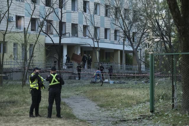 Des policiers inspectent un bâtiment endommagé par une frappe russe à Kiev. [Keystone/AP Photo - Wladyslaw Musiienko]