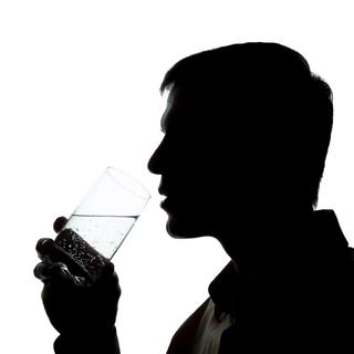 La silhouette d'un homme en train de boire un verre d'eau. [Depositphotos - Alexey_M]