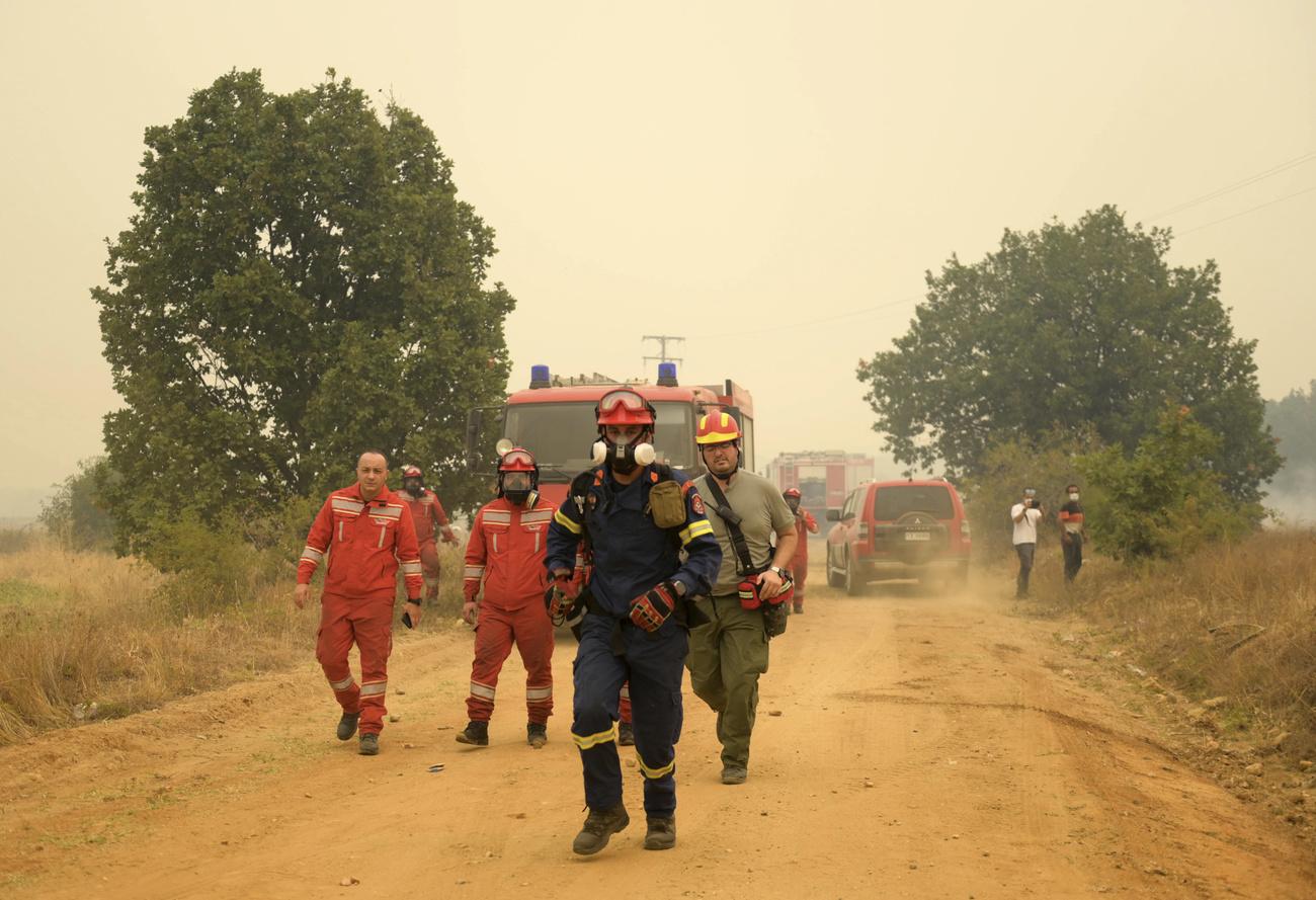 Les pompiers opèrent lors d'un incendie de forêt dans le village grec de Giannouli. [Keystone]