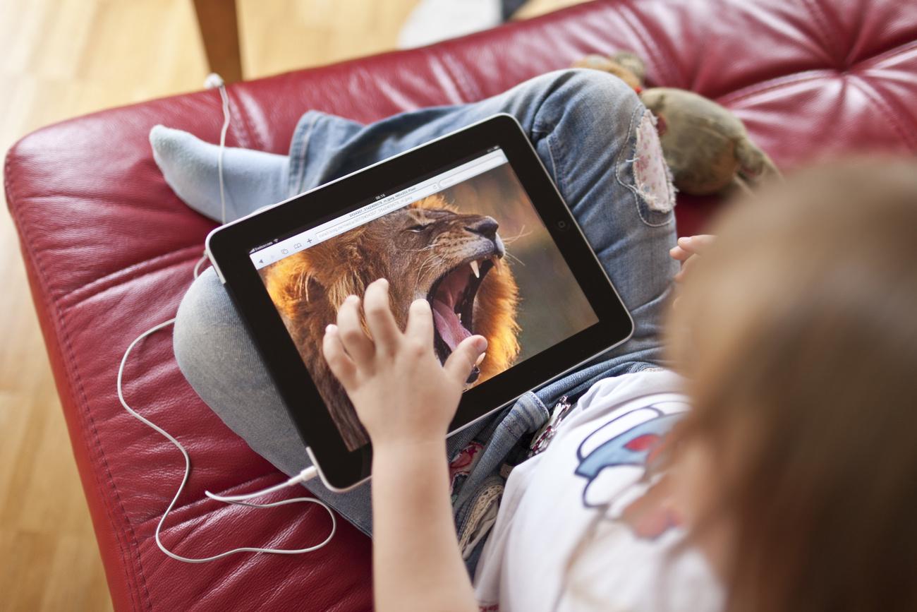 Une enfant regarde un documentaire animalier sur un iPad. [Keystone - Gaetan Bally]