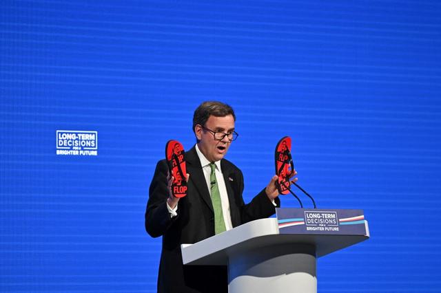 Greg Hands a raillé les "volte-face" de Keir Starmer en brandissant à la tribune des tongs (flip-flop en anglais, qui veut aussi dire volte-face) à son effigie. [AFP - Justin Tallis]