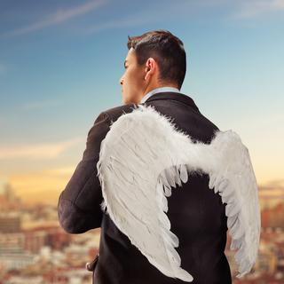 Un homme aux ailes d'ange observe une grande ville. [Depositphotos - Nomadsoul]