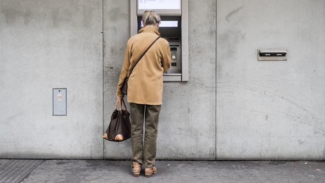 Une femme âgée devant un distributeur d'argent à Zürich (image d'illustration). [Keystone - Christian Beutler]