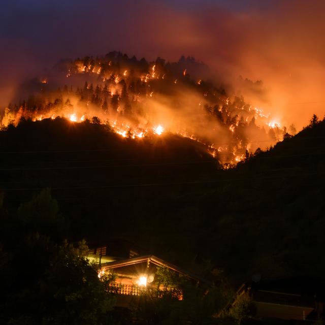 De la fumée et des flammes s'échappent de la forêt en feu au-dessus des communes de Bitsch et Ried-Mörel. [Keystone - Jean-Christophe Bott]