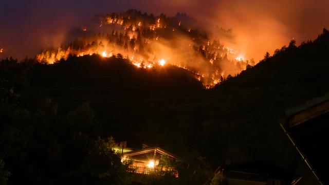 De la fumée et des flammes s'échappent de la forêt en feu au-dessus des communes de Bitsch et Ried-Mörel. [Keystone - Jean-Christophe Bott]