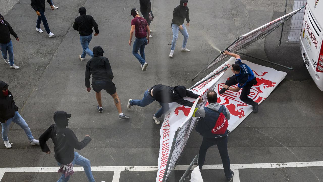 Les supporters ultras de bellinzone affrontent la police lausannoise près du car de l'équipe tessinoise après le match samedi. [Keystone - Jean-Christophe Bott]