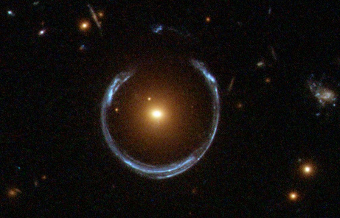 Sur cette photographie, la gravité d'une galaxie rouge lumineuse a déformé la lumière d'une galaxie bleue beaucoup plus éloignée: c'est l'effet dit de lentille gravitationnelle. En général, une telle déformation donne lieu à deux images discernables de la galaxie lointaine mais, ici, l'alignement de la lentille est si précis que la galaxie d'arrière-plan est déformée en un fer à cheval – un anneau presque complet. Cet effet de lentille ayant été prédit en détail par Albert Einstein il y a plus de 70 ans, les anneaux de ce type sont aujourd'hui connus sous le nom "anneaux d'Einstein". [APOD/NASA - ESA/Hubble]