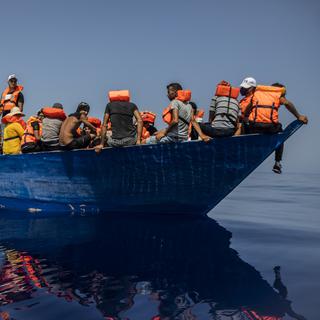 Un groupe de migrants tunisiens à bord d'une embarcation précaire en bois attend d'être aidé par une équipe de l'ONG espagnole Open Arms, au sud-ouest de l'île italienne de Lampedusa, le 29 juillet 2021. [Keystone - AP Photo/Santi Palacios]