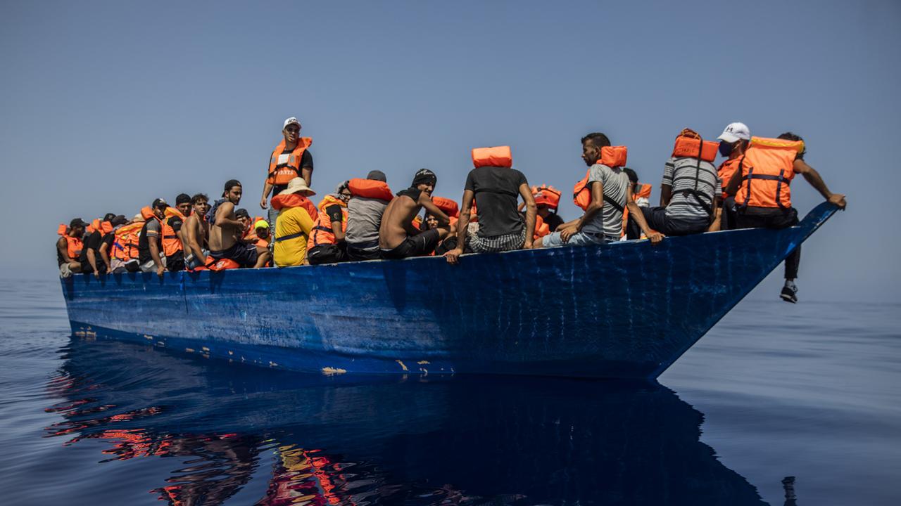Un groupe de migrants tunisiens à bord d'une embarcation précaire en bois attend d'être aidé par une équipe de l'ONG espagnole Open Arms, au sud-ouest de l'île italienne de Lampedusa, le 29 juillet 2021. [Keystone - AP Photo/Santi Palacios]