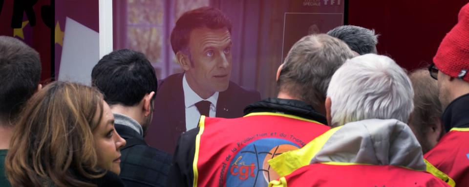 Des employé-e-s du service de nettoyage public en grève regardent le discours du président français Emmanuel Macron, le 22 mars 2023. [Keystone/AP Photo - Christophe Ena]