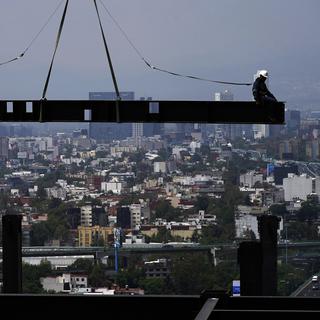 Des travailleurs de la construction en équilibre sur une barre de métal, dans la capitale du Mexique en 2022. [Keystone/AP Photo - Marco Ugarte]