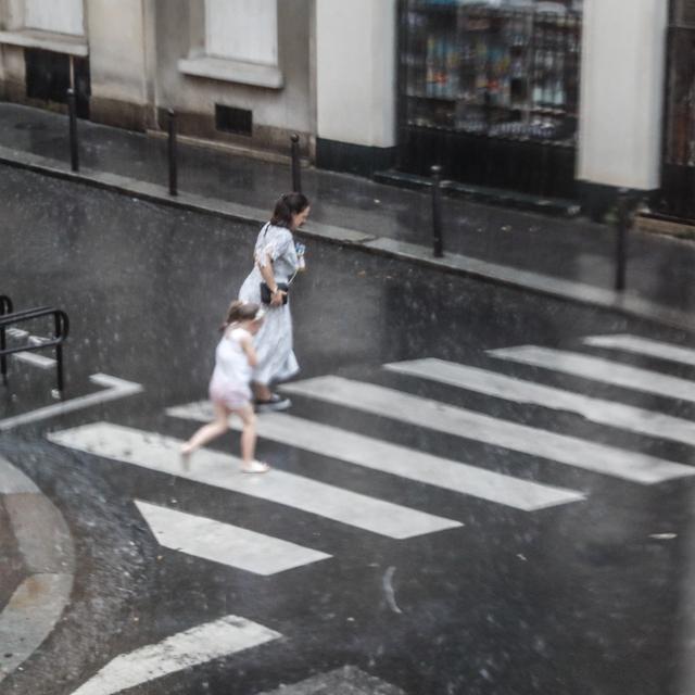 Une femme et sa fille courent sous la pluie à Paris. [AFP - Laure Boyer]