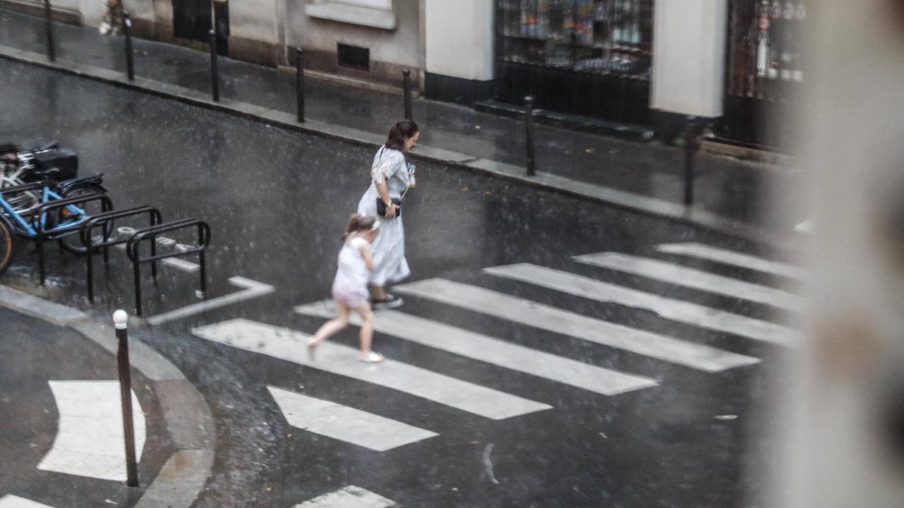 Une femme et sa fille courent sous la pluie à Paris. [AFP - Laure Boyer]