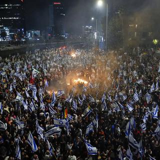 Des milliers d'Israéliens sont allés manifester dans la rue après le limogeage de Yoav Galant. [Keystone/AP - Ohad Zwigenberg]