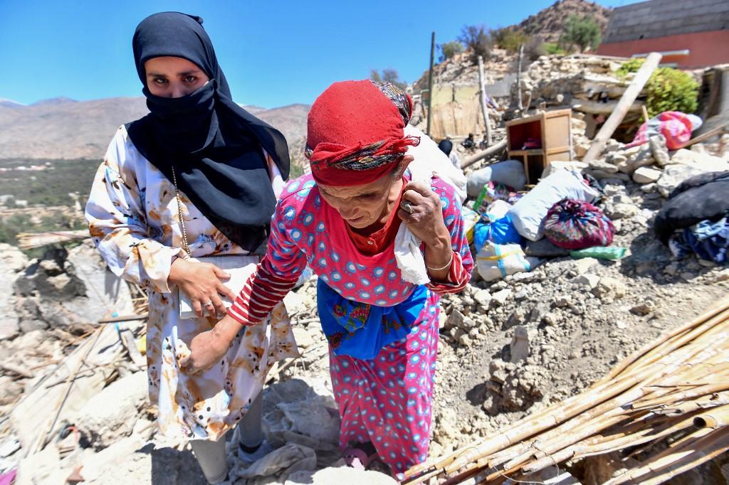 Des femmes marchent sur les décombres des maisons du village d'Imoulas. [AFP - Fethi Belaid]