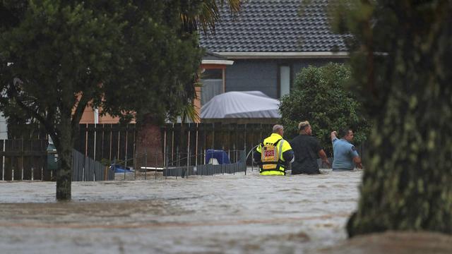 Des secouristes et un homme pataugent dans les eaux à Auckland, en Nouvelle-Zélande, le 27 janvier 2023. [Keystone - Hayden Woodward/New Zealand Herald via AP]