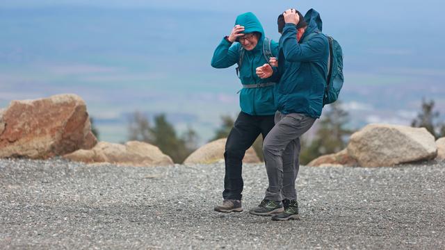 Un couple de touristes face au vent. [Keystone - DPA/Matthias Bein]